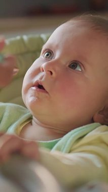 Sevimli bir bebek, masumiyetin ve merakın özünü yakalayan meraklı gözlerle yukarı bakar.