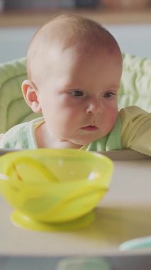 Meraklı bir bebek dikkatle parlak, sarı bir kâseye bakar. Masumiyet ve merak uyandırır.