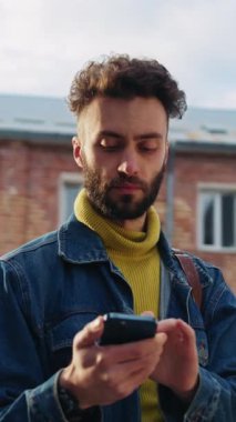 Akıllı telefonuna dalmış, şehir yaşamını ve modern iletişimin özünü resmeden genç bir adam.