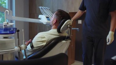 Erkek dişçi, hafif diş kliniğinde hastayı ameliyata hazırlıyor. Hydience ve sağlıklı.