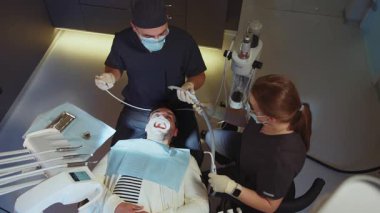 Tıbbi maskeli asistanı olan üst düzey bir dişçiden diş tedavisinde kullanılan bir diş aleti. Hydience ve sağlıklı.