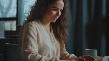 Laptopun önünde oturan, sosyal medyada gezinen, yorum yapan kıvırcık saçlı beyaz bir kadının yatay çekimi. Blog. Boş zaman. Hafta Sonu.