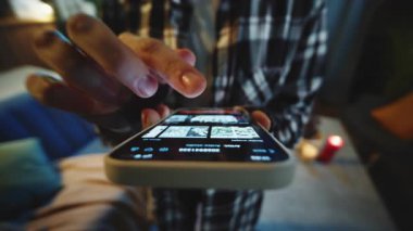 Ekose tişörtlü, elinde akıllı telefon olan ve internet üzerinden yayın yapan genç bir kadının görüntüsü. Ağır çekim. Eğlence. Akşam vakti. Kapalı