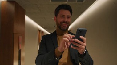 Yakından şık ceketli genç adam telefonda daktilo kullanıyor iş merkezindeki evlere bakıyor. Arka planda modern tasarım