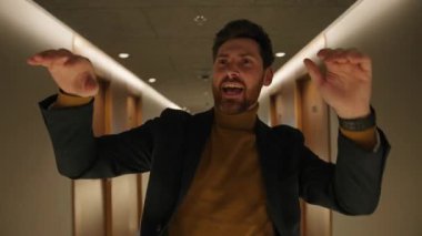 Otel koridorunda dans eden yakışıklı, mutlu iş adamı pozları. Duygusallık. Konuşarak. Gülümsüyor