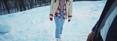 Güzel görünümlü genç bir kadının kış günü erkek arkadaşıyla güzel bir kar ormanında yürüdüğü görüntüler. Adam yardım ediyor ve kızın tırmanmasına yardım ediyor. Çiftler doğanın tadını çıkarıyor. Dağlar