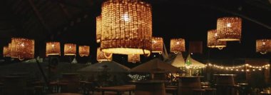 Restoran terasında güzel, modern iç mekânlı bir gece. Parlayan avizeler ve dışarıda elektrik ampulleri. Masalar. İnsan yok. Anamorfik lens