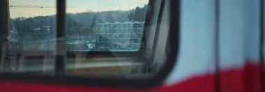 Bir tren penceresi, arka planda inşaatın sakin doğayla buluştuğu çarpıcı şehir manzarasını güzel bir şekilde yansıtır.