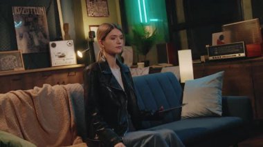 Mutlu genç kadın koltukta oturup gülümseyen ve evinde dinlenen tablet bilgisayar kullanıyor. Gece vakti.