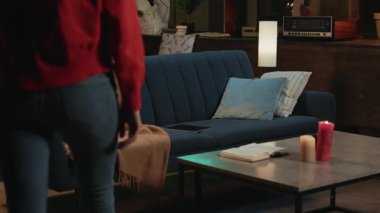 Kırmızı kazaklı kadın tablet bilgisayar kullanıyor kanepeye oturmuş gülümsüyor ve evde rahatlıyor. Gece vakti.