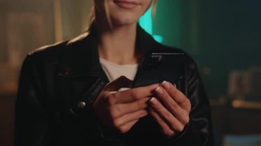 Sarışın genç bir kadın akıllı telefon yazısıyla modern odada mutlu olur. Gece lambası