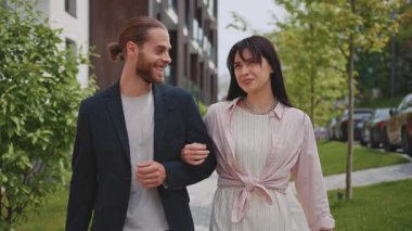 Sokakta yürüyen, konuşan ve dışarı bakan mutlu genç bir çift. Dinlenme zamanı. Randevu. Portre