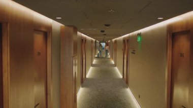 Güzel kızıl iş kadını ve zarif sarışın annenin hafta sonu tatil merkezinde çekilmiş görüntüleri. Modern otel koridorunda birlikte yürüyen ve bavulları yuvarlayan kadınlar. Kapalı