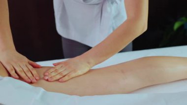 Sakin spa merkezindeki masaj masasında uzanmış rahat genç bir kadını vurmak. Kadın masajcının elleri içeride rahat ve sakin bir atmosferde bacağına masaj yapıyor. Gündüz