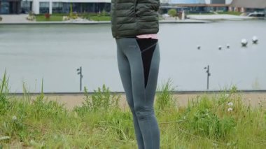 Yakından bakınca İskandinav yürüyüş çubuklarını kullanarak yeşil orman parkında göl kıyısında duruyor. Eğitimini al. Bulutlu hava