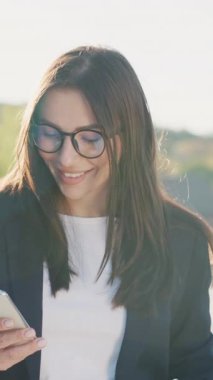 Şehir merkezinde gün ışığında telefonla yürüyen çekici bir kadın göl kenarındaki parka bakıyor. Cep telefonu olan bir portre kızı. Yavaş çekim