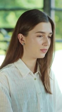 Çekici, çalışan, bilgisayarını kullanarak kameraya bakan, gülümseyen genç bir kadın aydınlık ofiste mutlu hisseder. Modern çalışma alanı. Teknoloji. Girişimci. İş kadınıyım. Yavaş çekim