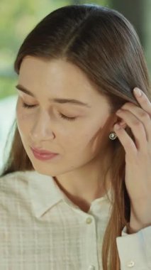 Saçlarına dokunan ve güneş ışığı ofisindeki kameraya bakan sevimli genç bir kadın. Başarılı bir iş kadını. Motive olmuş bir işveren. Gülümseyen işçi. Yavaş çekim