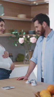 Aile anları. Ebeveynler. Hamile, genç ve mutlu bir kadın. Yakışıklı kocası gülümsüyor. Bebeğin mutfakta birlikte yemek yapmasını bekliyor..