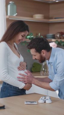 Aile hayatı. Neşeli bir çift Kafkasyalı genç ebeveyn, mutfakta çocuk kucaklaşması bekliyor. Hamile bir kadın. Sağlık hizmetleri. Ebeveynlik kavramı.