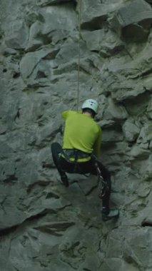 Kireçtaşından kayalıklara tırmanan kask takan genç sakallı dağcı. Dağcı dikkatle ormanın derinliklerine tırmanıyor. Ekstrem sporlar.