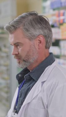 Modern eczacı dükkanında beyaz sakallı, profesyonel, olgun, yetişkin bir erkek eczacıya yakın çekim. Eczanede danışman. Eczacı..