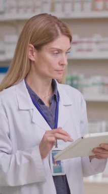 Profesyonel kadın danışman eczane dijital tabletle tıp öğreniyor, İnternet 'te ilaç detaylarını araştırıyor. Kimya. Tıp sektörü.