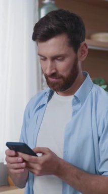 Akıllı telefonunu şık ve çağdaş bir yaşam ortamında kullanırken dikkatle odaklanan bir adam.