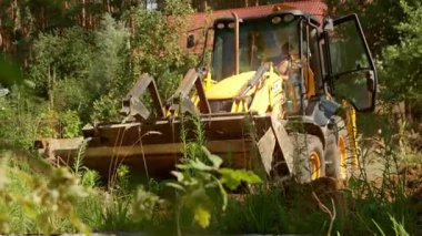 Bu video, yeşil bir ormanda yol alan damperli kamyon ve buldozer gibi güçlü sarı inşaat araçlarını gösteriyor. Arazi yönetimindeki rollerini vurguluyorlar.