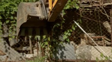 Bu video, çit ve çitin yanında bir buldozer kazarken, sarı bir kazıcının yeşil bir tarlayı kazarak inşaatı vurguladığı ağır makineler içeriyor.
