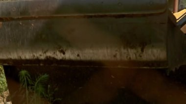 Video, sarı buldozer ve JCB traktörlü bir inşaat sahnesi gösteriyor. Kapanışlar paslı bir yüzeyi vurguluyor, buldozer çamurla çalıştığı için karakter ekliyor