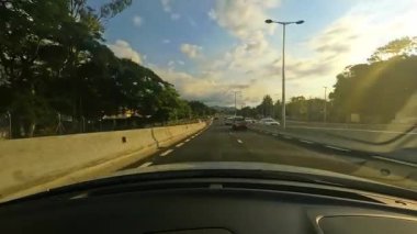 Bir araba güzel manzaralarda hareket ederken manzaralı bir yolculuk yaşayın. Video, doğanın huzurunu, günbatımını ve kentsel sokakları gösteriyor.