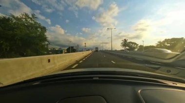 Güneş ışığı ön camdan süzülüp, içini sıcak renklere boyarken huzurlu bir sürüşün tadını çıkar. Kamera gün batımında dolambaçlı bir otoyolu yakalar, izleyicileri açık yolun özgürlüğünü kucaklamaya davet eder.