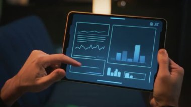 Bir kişi, tablet ekranında etkileşimli veri analizleriyle uğraşır, modern dijital ortamda grafikler ve istatistikler gösterir.