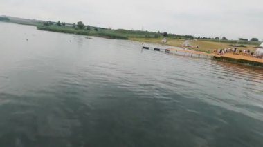 Yaz Gölü. Sinema kırsal manzaralı güzel bir FPV. Yüzmeyi, yelkenli kullanmayı ve güneşlenmeyi seven bir sürü insan var. Sezon tatili kavramı.