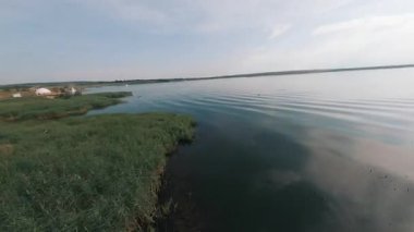 Güzel kırsal kesimde FPV hava aracı. Huzurlu nehir düz su manzarası ve mavi gökyüzü. Yaz tatili. Tatil.