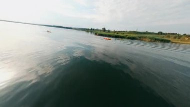 Resimli kırsalda İHA uçuşu. Huzurlu nehrin muhteşem kırsal manzarası, yüzen kuşlar ve yeşil çayırlar. Güneş ışığı. Yaz zamanı..