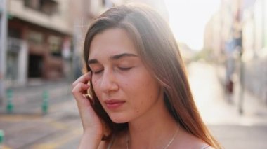 Kameraya gülümseyen çilli güzel bir kadının portresi. Düz saçlı güzel beyaz bir kız. Açık havada. Bulanık cadde.