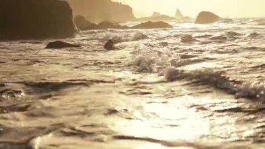 Vahşi karanlık kayalar, barışçıl dalgalar ve turuncu gökyüzü ile güzel bir kıyı manzarası var. Sahilde gün batımı. Tenerife, İspanya. Kanarya Adaları.