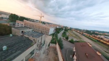 Gün batımında güzel şehir evleri ve gökdelenlerin havadan görünüşü. Yeni binaların konut inşaatı üzerinde uçuş. FPV İHA.