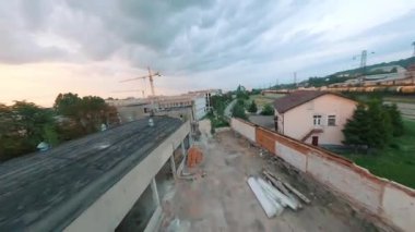 Modern yerleşim alanının inşaat sahasında uçuyor. Hava aracı FPV gün batımında güzel bir akşam şehri manzarası. Yaz havası. Konsepti keşfet.