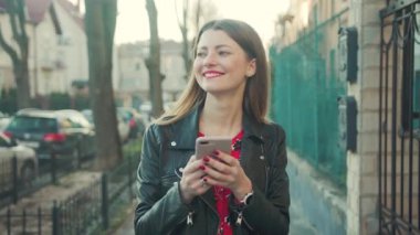 Los Angeles, Kaliforniya 15 03 03 2019 EDITORIAL: akıllı telefon ile sokakta yürüyen şık genç kadın. Aşık zarif kız gülümsüyor. Sokak, bahar zamanı. Tek başıma. Sabah erkenden. Dijital teknoloji.