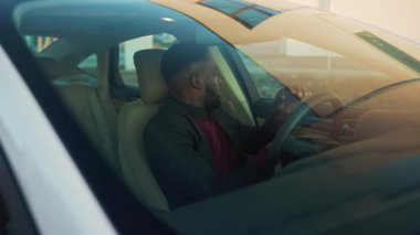 Aracın direksiyonunda oturan mutlu, genç, yakışıklı Afro-Amerikalı adam şöyle der: Araç kolu, araba sokağı otomobil işadamı yavaş çekimde ceketi satın alır.