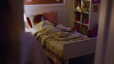 NEW YORK - 5 Nisan 2018: Anne küçük kıza masal okuyor. Annem çocukların yatak odasındaki ışığı hariç tutuyor. Kızıl kız, çocukların odasında uyur. Arri Alexa Mini Sinemada Çekim.