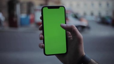 NEW YORK - 5 Nisan 2018: Dikey yeşil ekran akıllı mobil arka plan görünümlü telefon kullanan erkek elleri bulanık krom anahtar değiş tokuşu dokunmatik ekran dokunmatik açık hava iş dünyası interneti yavaş çekim dokunuşu