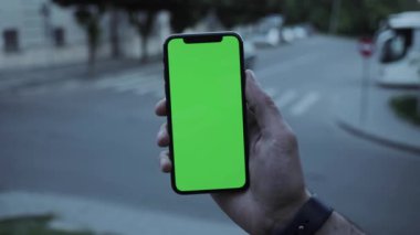 NEW YORK - 19 Nisan 2019: Dikey yeşil ekran akıllı mobil arka plan otomobil yol görüşlü erkek elleri bulanık krom anahtar değiş tokuşu ekran dokunmatik açık hava iş dünyası interneti yavaş çekim dokunuşu