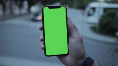 NEW YORK - 19 Nisan 2019: Boş yeşil ekran akıllı telefon mobil yakın plan görüntüsü kullanan adam eli bulanık arkaplan renk değiştirme ekranı dokunmatik ekranı işaret eden kaydırma kontrol eden haber uygulamaları indirme