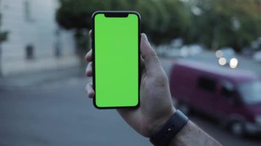 NEW YORK - 19 Nisan 2019: Dikey yeşil ekran mobil arka plan otomobil yol görüşlü telefon kullanarak erkek ellerini kapat bulanık krom anahtar değiş tokuş ederek dokunmatik ekran açık hava iş dünyası internet dokunuşları yavaş çekim