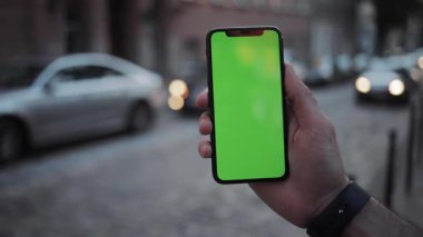 NEW YORK - 19 Nisan 2019: Yavaş çekim adamı elleri dikey yeşil ekran mobil arka plan otomobil yol görüşlü telefon kullanıyor bulanık kromaanahtar değiş tokuş yapıyor dokunmatik ekranı açık hava iş dünyası internet dokunuşunu kapat