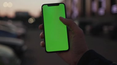 NEW YORK - 19 Nisan 2019: Akşam saatlerinde çekilen el kamerasında, arka planda dikey yeşil ekranlı akıllı telefon kullanın.